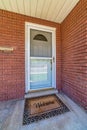 Gray front door and glass storm door at the entrance of home with red brick wall Royalty Free Stock Photo