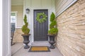 Gray front door of a home with green wreath and flanked by tall potted plants Royalty Free Stock Photo