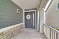 Gray front door with white holiday wreath and narrow sidelight at home facade Royalty Free Stock Photo