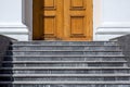 Gray granite stair steps at the entrance to the brown wooden door. Royalty Free Stock Photo