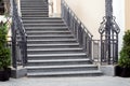 Gray granite staircase with stone steps climbing upward with iron railing.