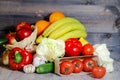 On a gray graphite wooden background, tomatoes in a box, cucumber, garlic, iceberg lettuce, large red peppers, bananas, oranges in Royalty Free Stock Photo