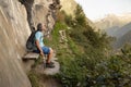 Gray-haired athletic man sitting on a wooden bench under a rock on a hiking mountain trail Royalty Free Stock Photo