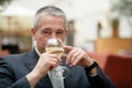 Gray-haired businessman drinking wine glass of mineral water