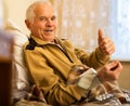 Gray haired elderly man measuring pressure with tonometer at home