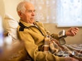 Gray haired elderly man measuring pressure with tonometer at home