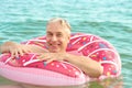 Gray-haired funny man swims on an inflatable circle in the sea