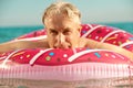 Gray-haired funny man swims on inflatable circle in the sea Royalty Free Stock Photo