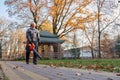 Gray haired maintenance worker cleaning sidewalk with leaf blower. Royalty Free Stock Photo