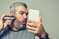 Gray-haired man cuts his beard with an electric clipper Royalty Free Stock Photo