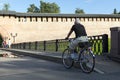 Gray-haired man in shorts riding his bike on the bridge in the d