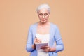 Gray haired old serious business woman wearing glasses, writing plans strategy in paper note book with pen. Isolated Royalty Free Stock Photo