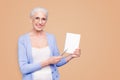 Gray haired old smiling business woman wearing glasses, showing blank page holding paper note book with pen. Isolated Royalty Free Stock Photo