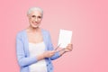 Gray haired old smiling business woman wearing glasses, showing blank page holding paper note book with pen. Isolated Royalty Free Stock Photo