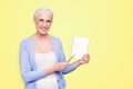 Gray haired old smiling business woman wearing glasses, showing blank page holding paper note book with pen. Isolated Royalty Free Stock Photo