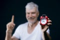 Gray haired senior man with alarm clock in his hands. Sport and health care concept