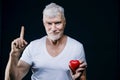 Gray haired senior man with a heart in his hands. Sport and health care concept