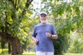 Gray-haired senior man in sportswear running in the park, doing a morning jog, doing sports, keeping fit and leading a Royalty Free Stock Photo