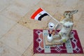 The gray hare stands on the rug holding the Egyptian flag in its paws and smoking a hookah, a scarecrow Royalty Free Stock Photo