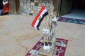 The gray hare stands on the rug holding the Egyptian flag in its paws and smoking a hookah, a scarecrow