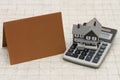 A gray house, brown card and calculator on stone background Royalty Free Stock Photo