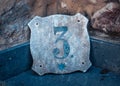 Gray house number plate in Catalonia. Street sign number 3 on old textured wall. Street scene. Royalty Free Stock Photo