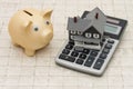 A gray house, piggy bank and calculator on stone background Royalty Free Stock Photo