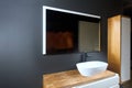 Gray industrial flat loft bathroom with modern wooden countertop, basin, illuminated mirror and wooden PVC cupboard with Royalty Free Stock Photo