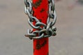 Gray iron chain is wound on a red rusty pillar Royalty Free Stock Photo