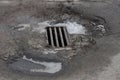 Gray iron grate of a drain on the dirty asphalt Royalty Free Stock Photo