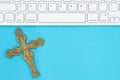 Gray keyboard with a religious cross on a blue paper Royalty Free Stock Photo