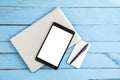 Gray laptop ,black tablet ,small paper notebook and black pen on blue wooden background. the view from the top Royalty Free Stock Photo