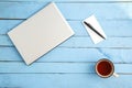A gray laptop, a Cup of drink,a small paper notebook and a black pen on a blue wooden background. the view from the top Royalty Free Stock Photo