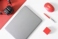 Gray laptop, pen, red computer mouse, red box and black wireless headphones on a red and white background. The concept of a modern Royalty Free Stock Photo