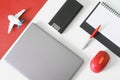 A gray laptop or ultrabook, a red computer mouse, a fountain pen, a diary, a power bank and a toy plane on a red and white table. Royalty Free Stock Photo