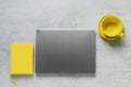 The gray laptop the yellow notebook and yellow cup on a grey concrete backgroundous yellow and extremely gray