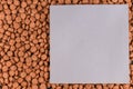 A gray and lilac piece of paper lies on top of the dog food. Brown pellets of dry pet food. Empty square sheet. Pet food. Copy