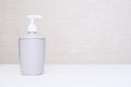 A gray liquid soap dispencer, bottle against white background in a bathroom with copy space