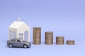 Gray machine model and home with coins in the form of a histogram on a purple background. Concept of lending, savings, sale, lease