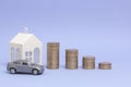 Gray machine model and home with coins in the form of a histogram on a purple background. Concept of lending, savings, sale, lease