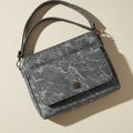 Gray marble-patterned handbag with a rectangular shape and dual handles. The bag Royalty Free Stock Photo