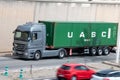 Mercedes Actros truck loading a green container trailer along Barcelona's Ronda Litoral