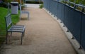 Gray metal benches, railing at the lookout, trash can in the park with a gravel beige path and lawn in summer