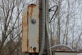 A gray metal box in brown rust and with electric wires