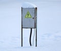 Gray metal electrical panel covered with snow with a high voltage danger sign Royalty Free Stock Photo