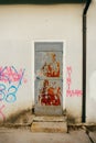 Gray metal entrance door in red rust, white wall