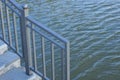 gray metal handrails and iron steps on the shore near the water of a reservoir Royalty Free Stock Photo