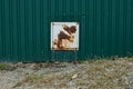 Gray metal square box for electrical wires in brown rust in the green iron wall