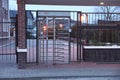 Gray metal turnstile and at the entrance and the fence wall