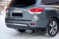 Gray Nissan Pathfinder 2015 year rear view with dark black interior in excellent condition in a parking space with snow background